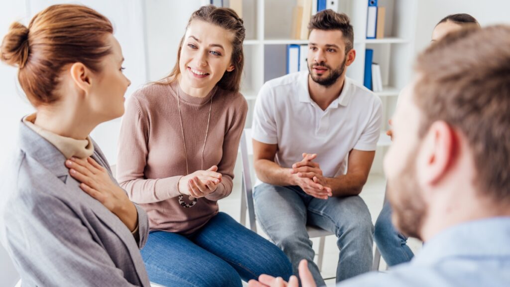 A woman shares her experiences during a group therapy exercise for residential rehab in michigan 
